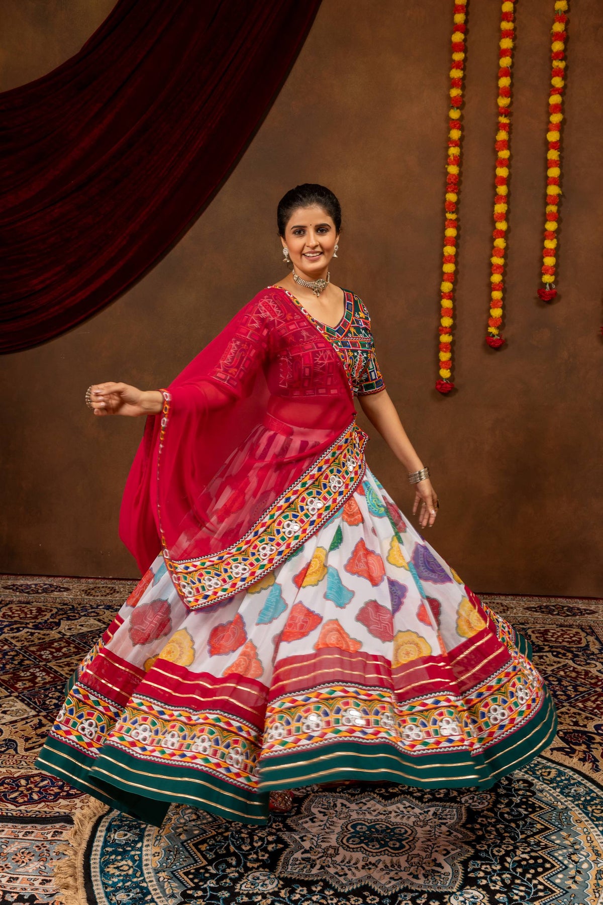 Model holding flared multicolor printed lehenga skirt with embroidered border and sheer pink dupatta