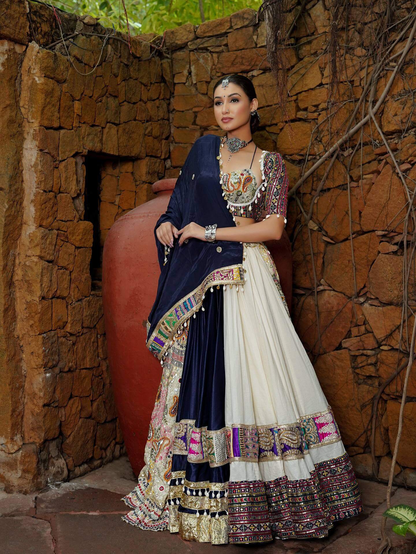 Standing full view of model wearing off-white and navy blue chaniya choli draped with bordered navy dupatta