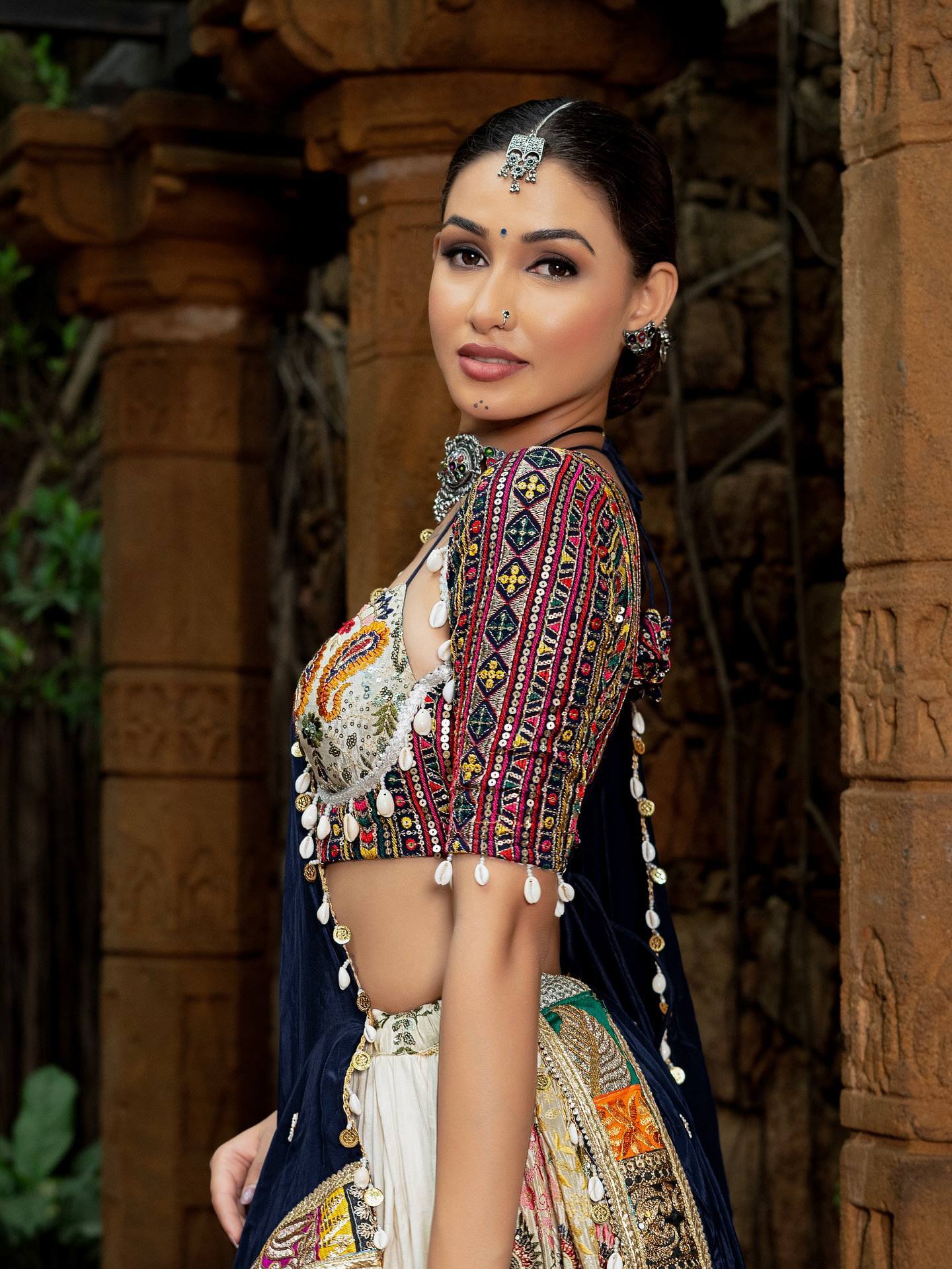 Close-up side angle of multi-pattern embroidered blouse with cowrie shell hangings and coin tassels