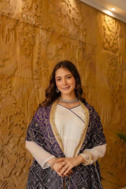 Mid-shot portrait of model wearing an off-white angrakha kurta styled with a deep purple and gold printed dupatta