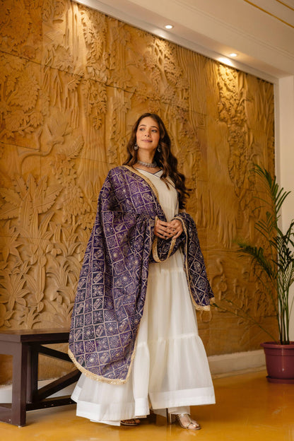 Full-length view of an off-white flared anarkali suit styled with a deep purple patterned dupatta draped over both arms