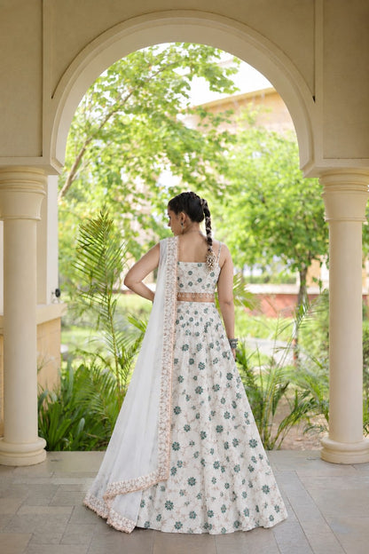 Full-length back view of a model in an off-white floral embroidered flared lehenga with a square-back spaghetti strap blouse.