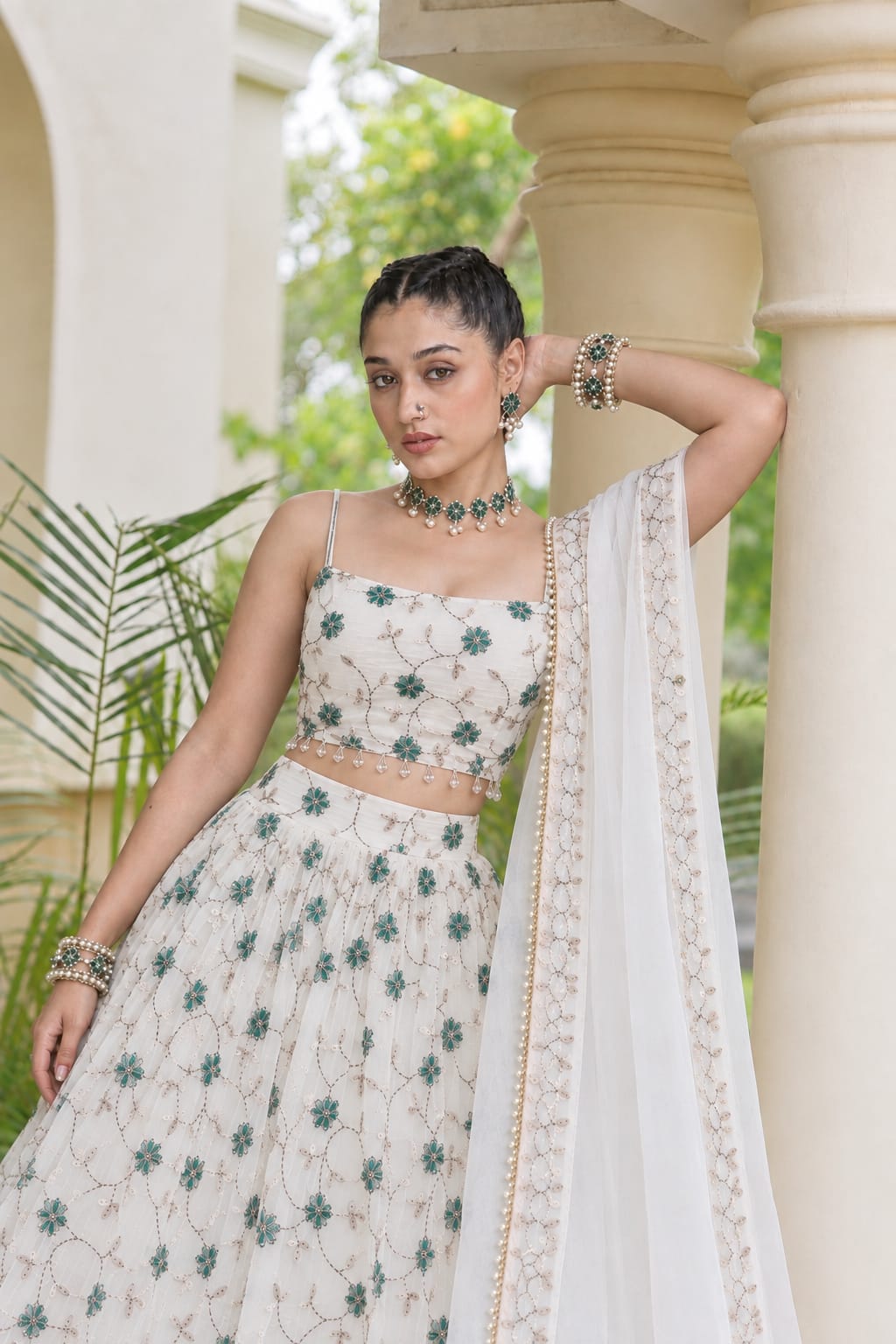 Mid-shot view highlighting the green floral embroidery and delicate pearl drop fringe on an off-white spaghetti strap lehenga blouse.