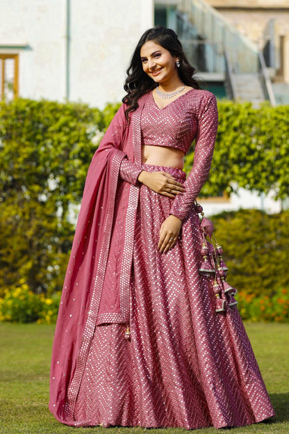 Three-quarter shot highlighting the V-neckline, chevron mirror pattern, and heavy waist tassels of an onion-pink lehenga set.