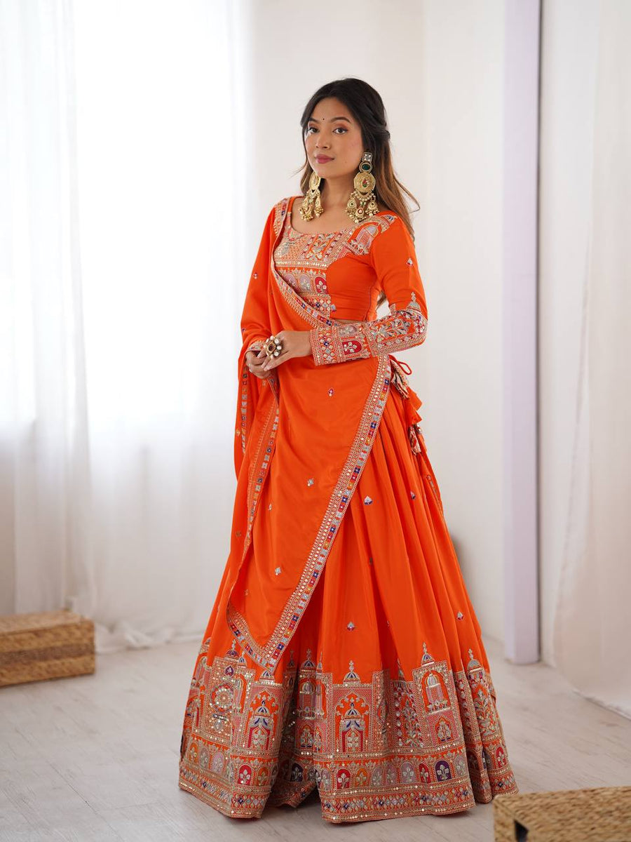 Full-length front shot of model in an orange pleated lehenga set featuring multicolored jharokha motif border