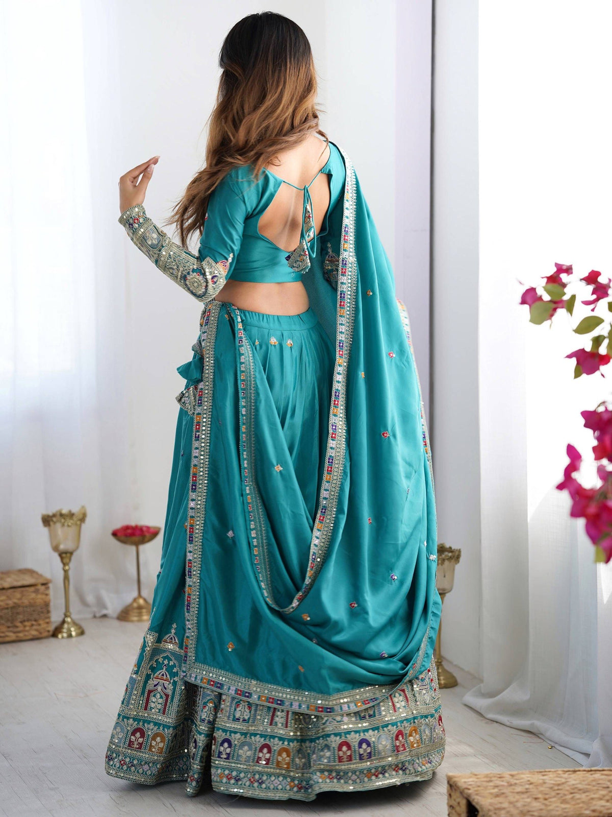 Back view of model wearing peacock blue lehenga choli with tie-up back blouse and embroidered skirt