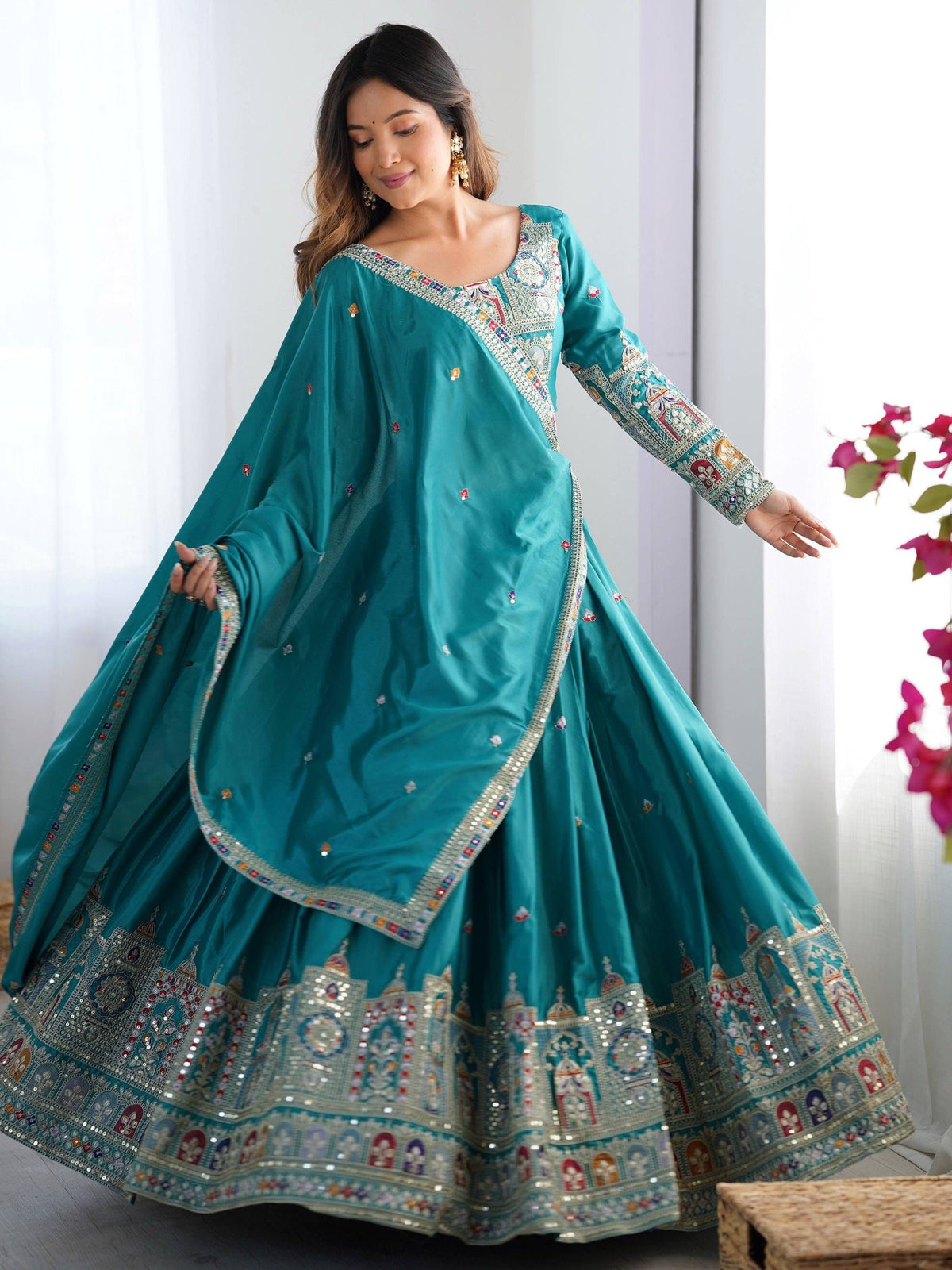 Standing front pose of model displaying the wide flare and border detailing of peacock blue lehenga set