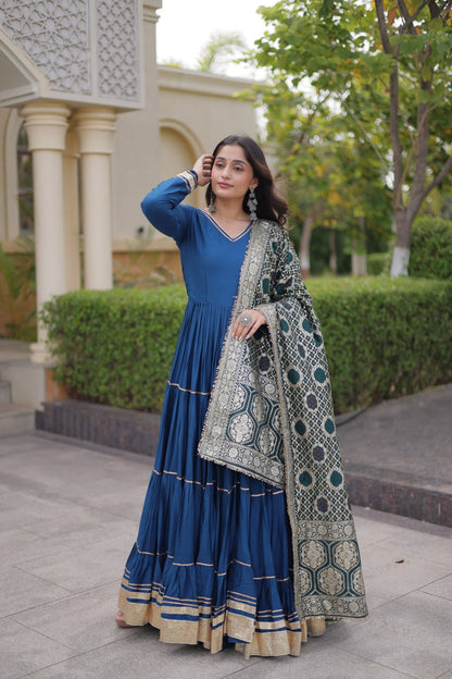 Full-length shot of a model showcasing a peacock blue V-neck tiered anarkali gown styled with a rich woven Banarasi Bandhani dupatta.