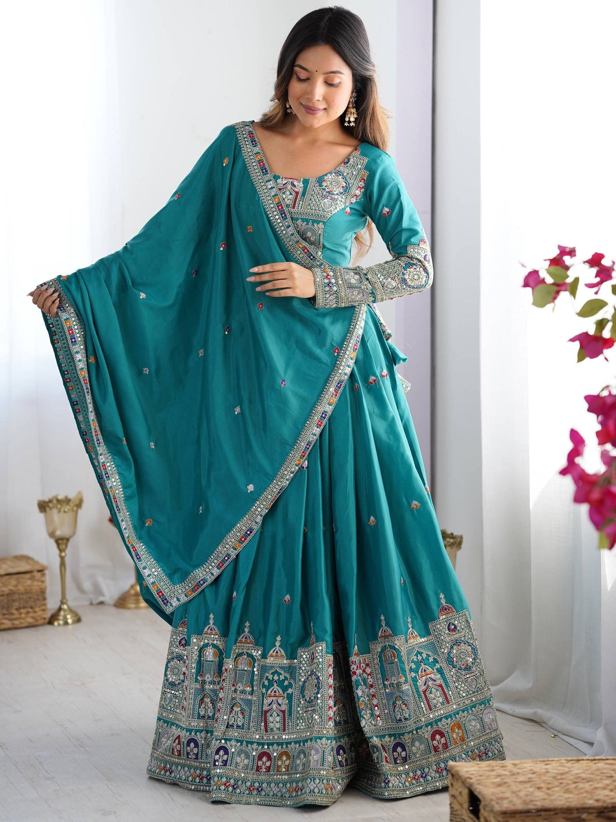 Model wearing peacock blue pleated lehenga choli with full-sleeve embroidered blouse and dupatta