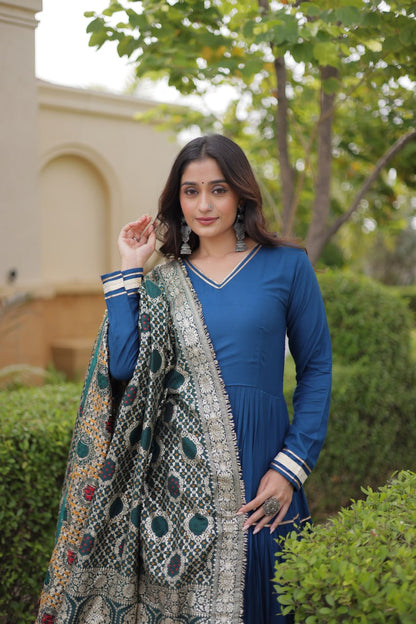 Close-up mid-shot portrait of a model draping a dark green and gold woven jacquard dupatta over a solid peacock blue gown.