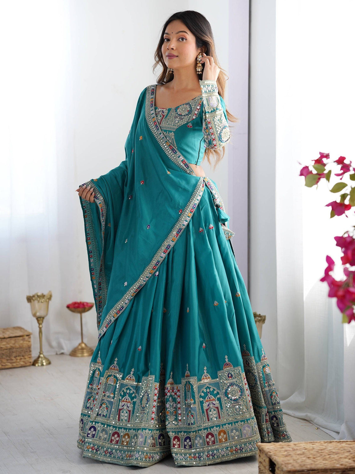 Full-length front shot of model in peacock blue pleated lehenga choli with heavy architectural border work