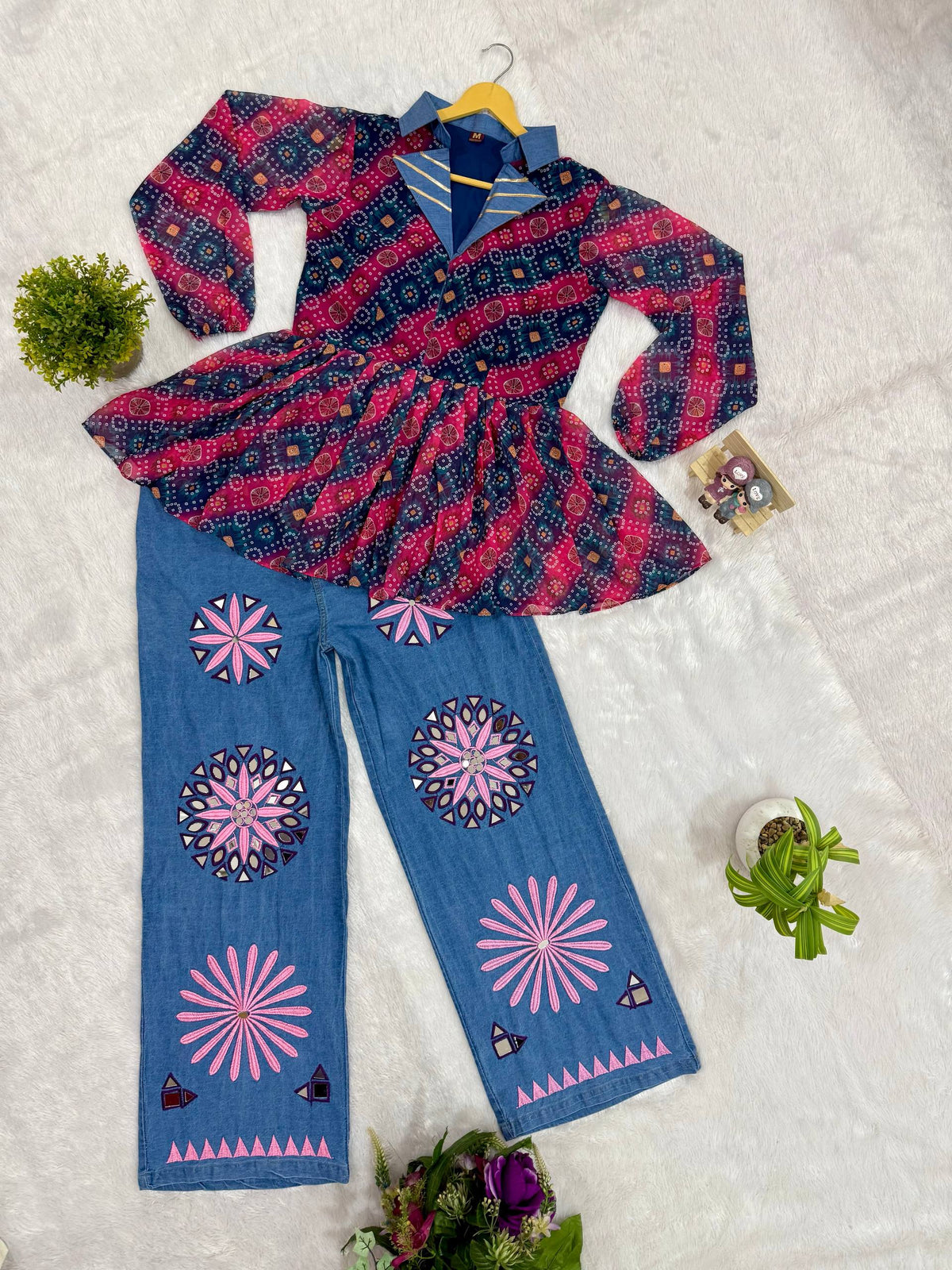 Flat lay view of pink and blue bandhani printed peplum top with denim lapel collar and mirror-embroidered wide-leg jeans