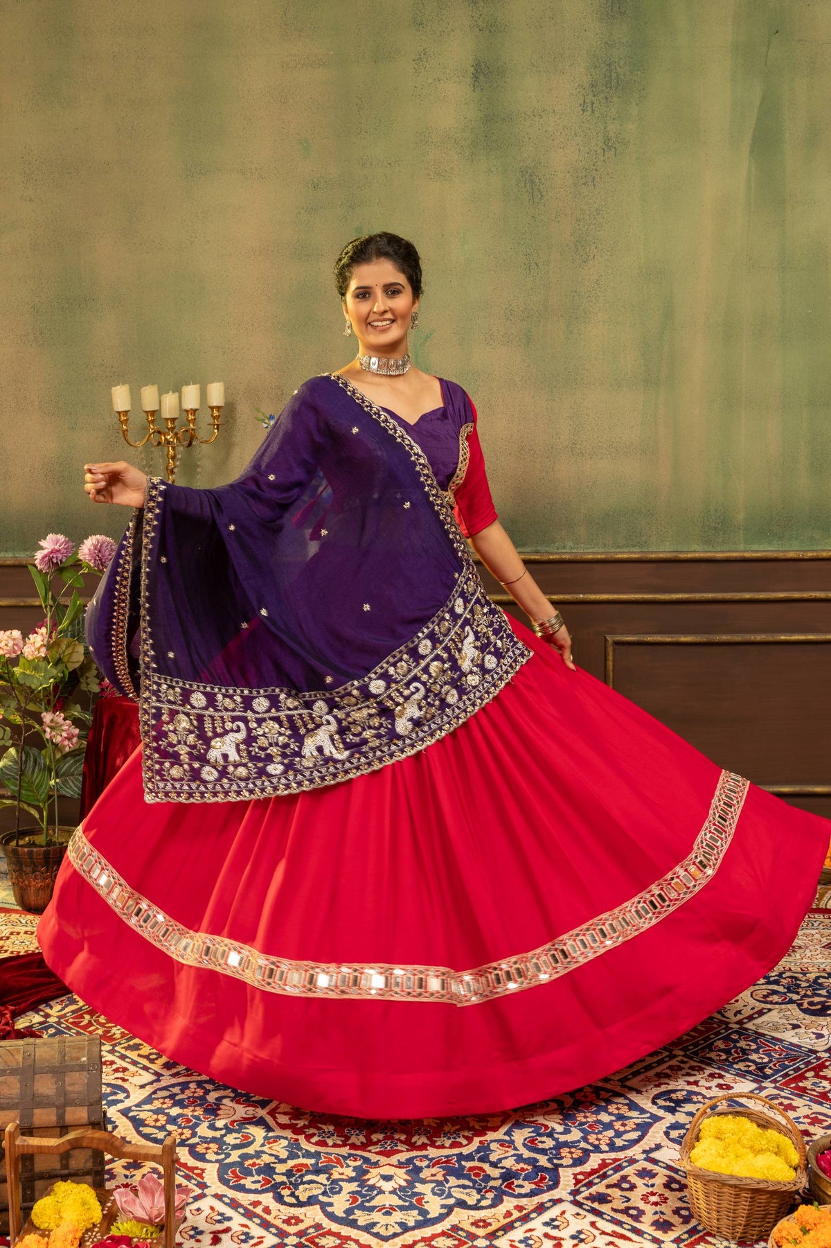 Full flared view of model presenting pink lehenga skirt with gold mirror lace border and purple draped dupatta