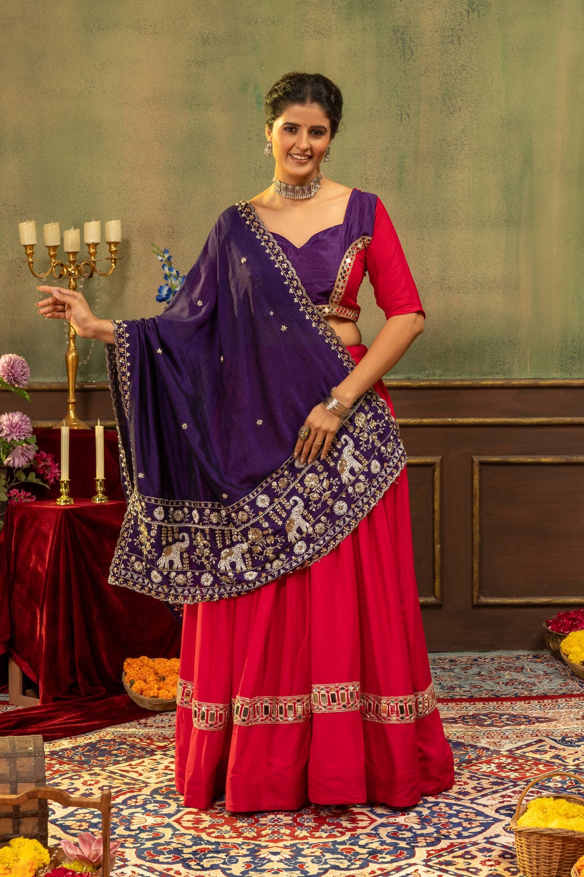 Full-length front view of model in pink lehenga skirt paired with purple dupatta featuring embroidered elephant borders