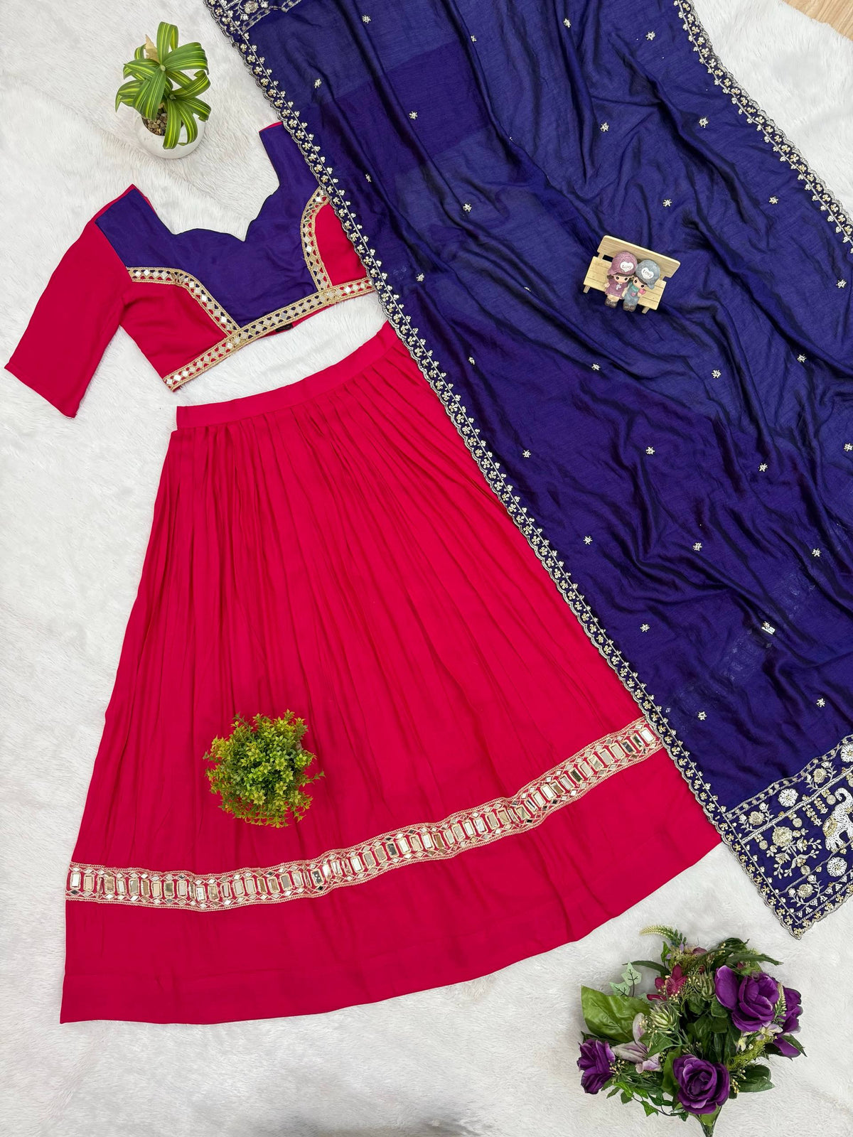 Flat lay view of pink pleated lehenga, dual-tone pink and purple blouse, and purple embroidered dupatta