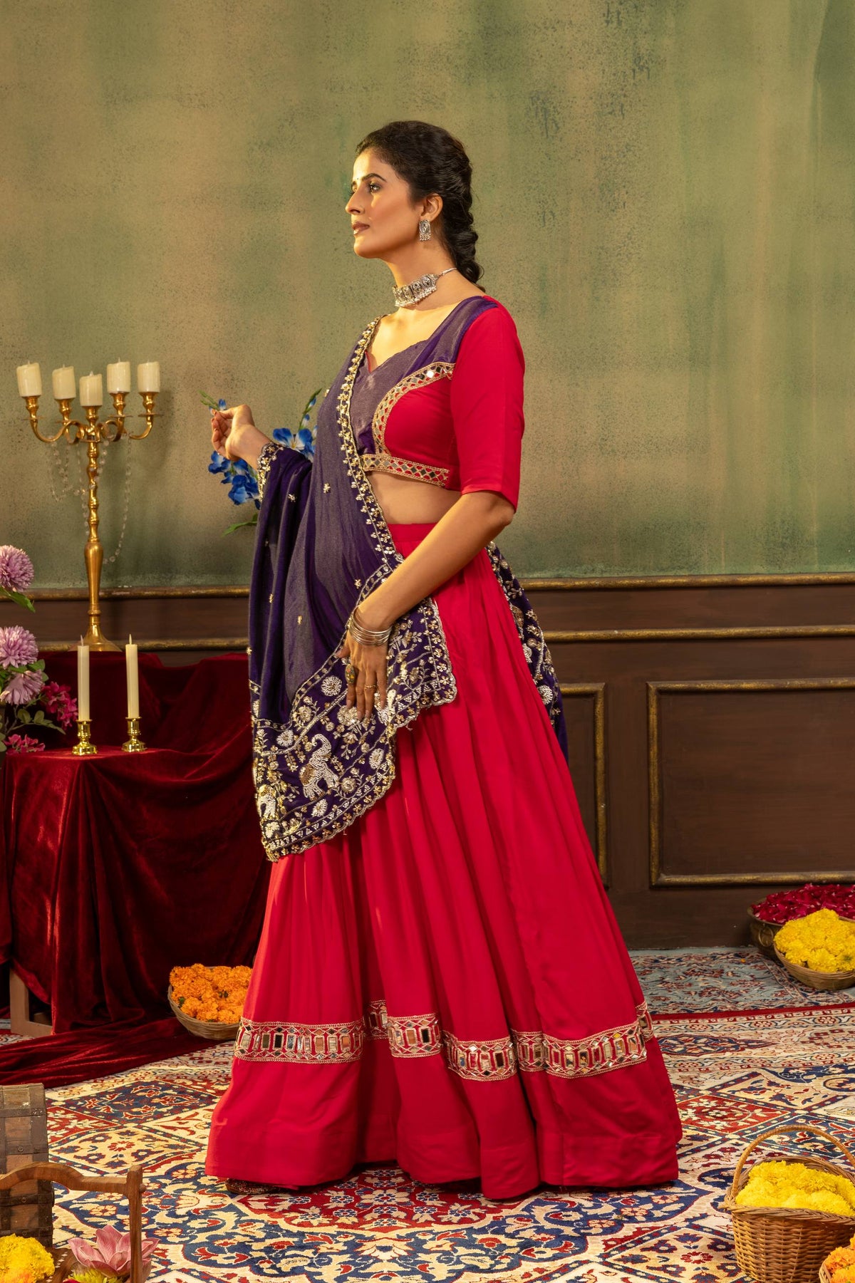 Side profile view of model wearing pink pleated lehenga choli with draped purple elephant motif dupatta