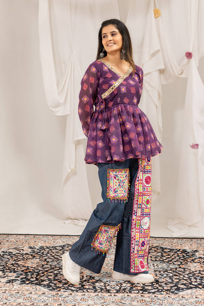 Three-quarter standing pose of model in purple printed flared tunic top paired with embroidered wide-leg jeans