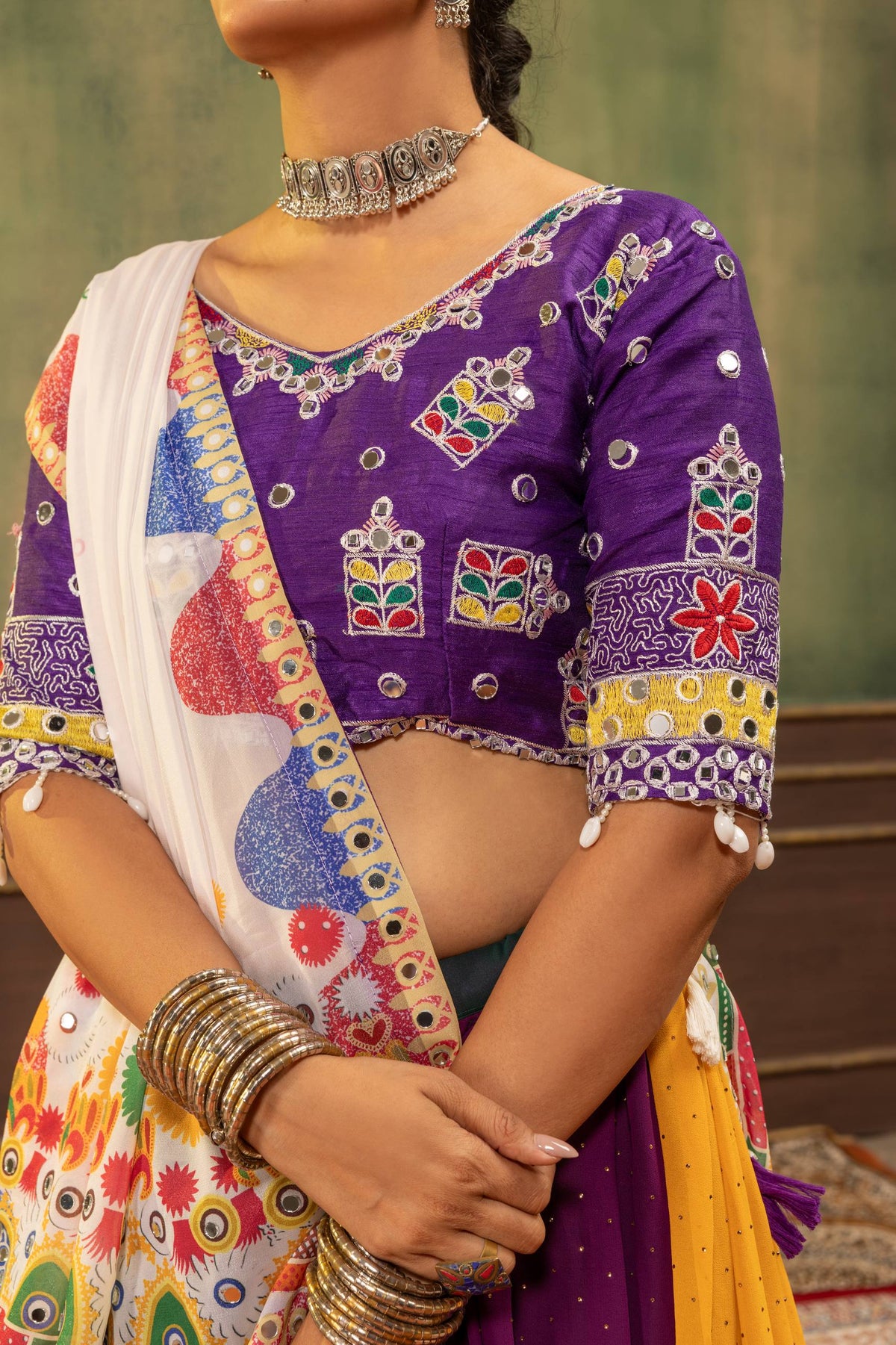 Close-up front view of purple elbow-sleeve blouse with Kutchi-style geometric mirror embroidery and hanging cowrie beads