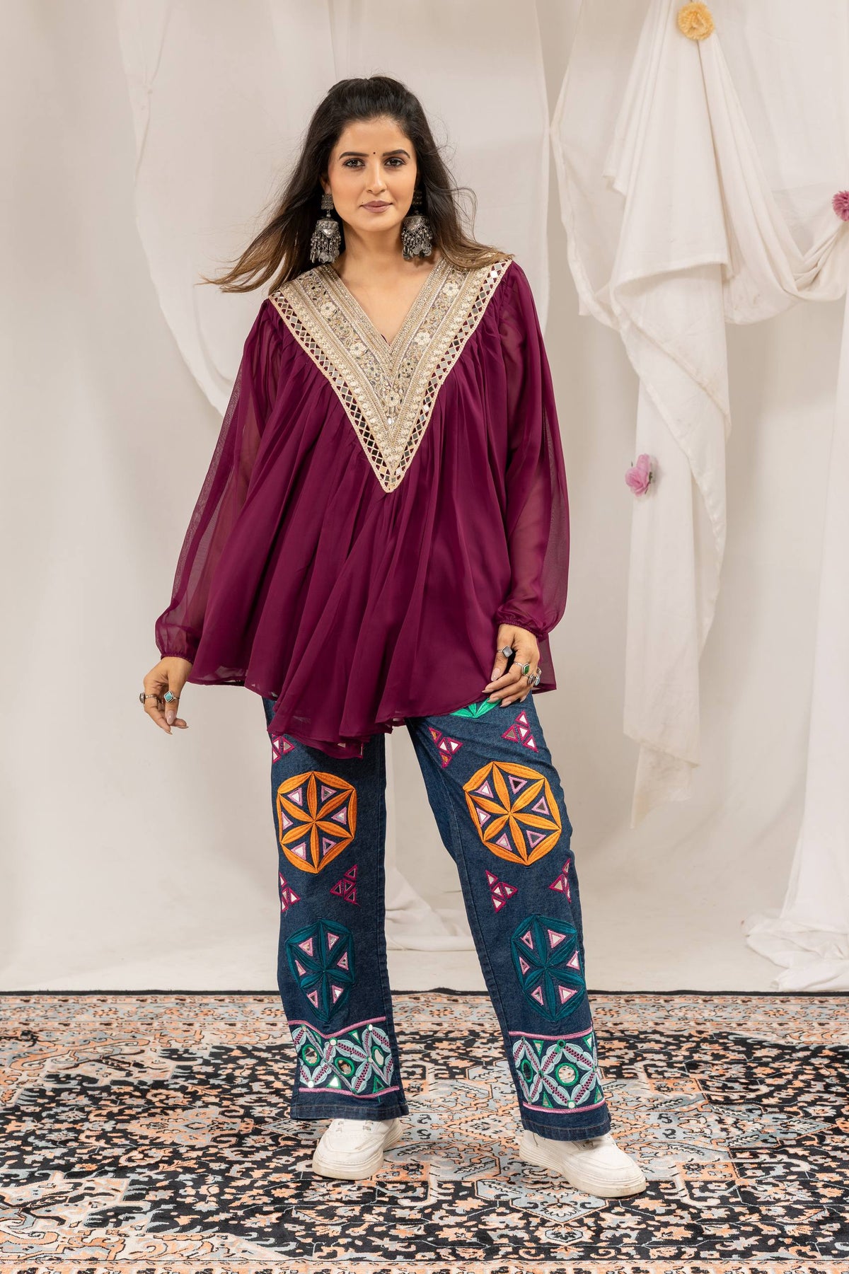 Full standing front view of purple tunic top paired with wide-leg blue jeans featuring multi-color embroidery