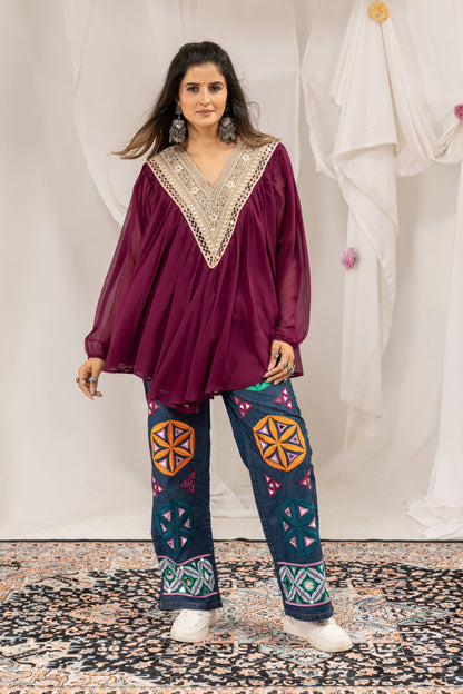 Full standing front view of purple tunic top paired with wide-leg blue jeans featuring multi-color embroidery