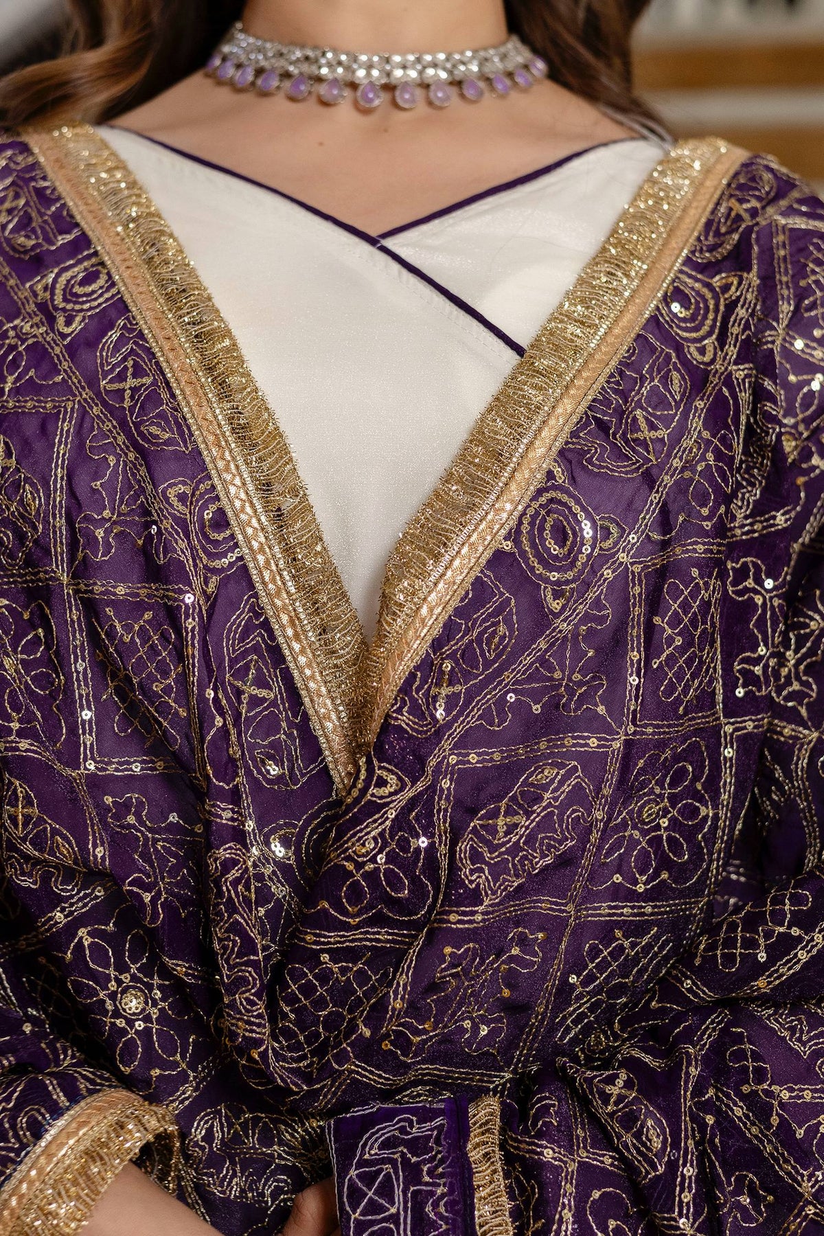 Close-up shot of deep purple dupatta with geometric gold foil patterns and zari fringe border over an off-white angrakha neckline
