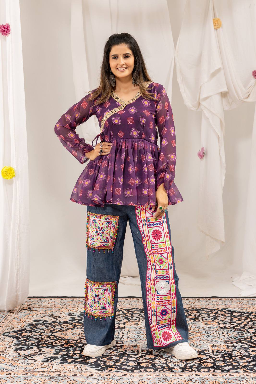 Full-length front view of model posing in purple printed angrakha peplum top and embroidered denim trousers