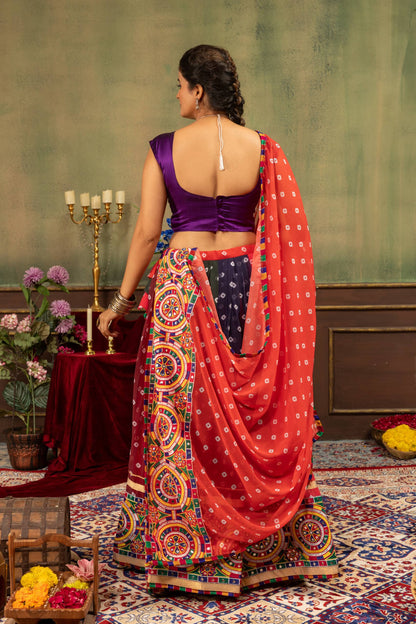 Back view of model wearing purple sleeveless blouse and flared bandhani skirt with draped red dupatta
