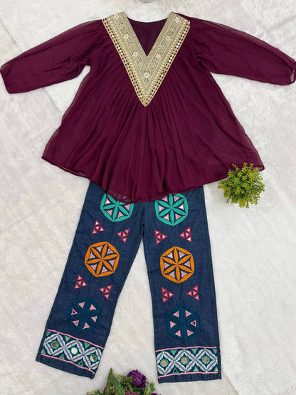 Flat-lay display of purple v-neck tunic top and blue jeans with colorful geometric embroidery and mirror work
