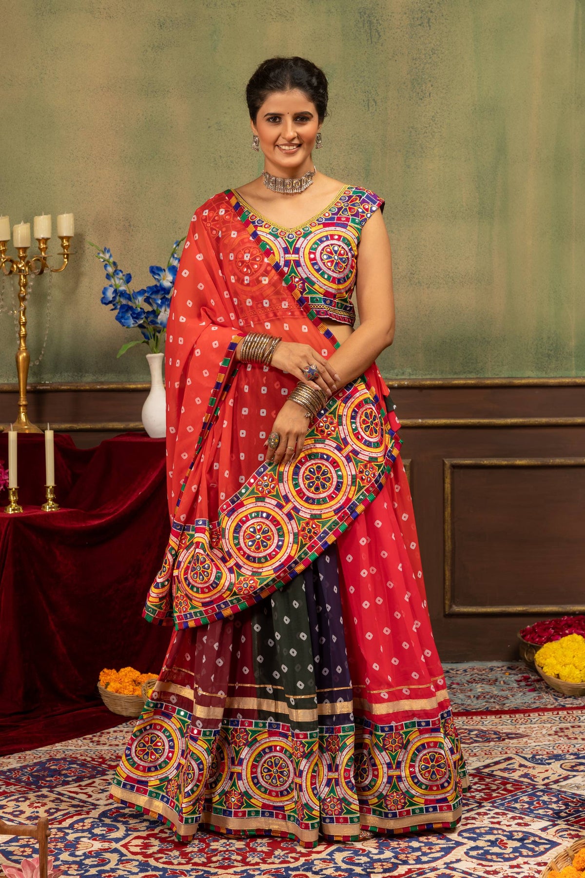 Model standing in red panelled bandhani chaniya choli with diagonal draped dupatta featuring mirror work border