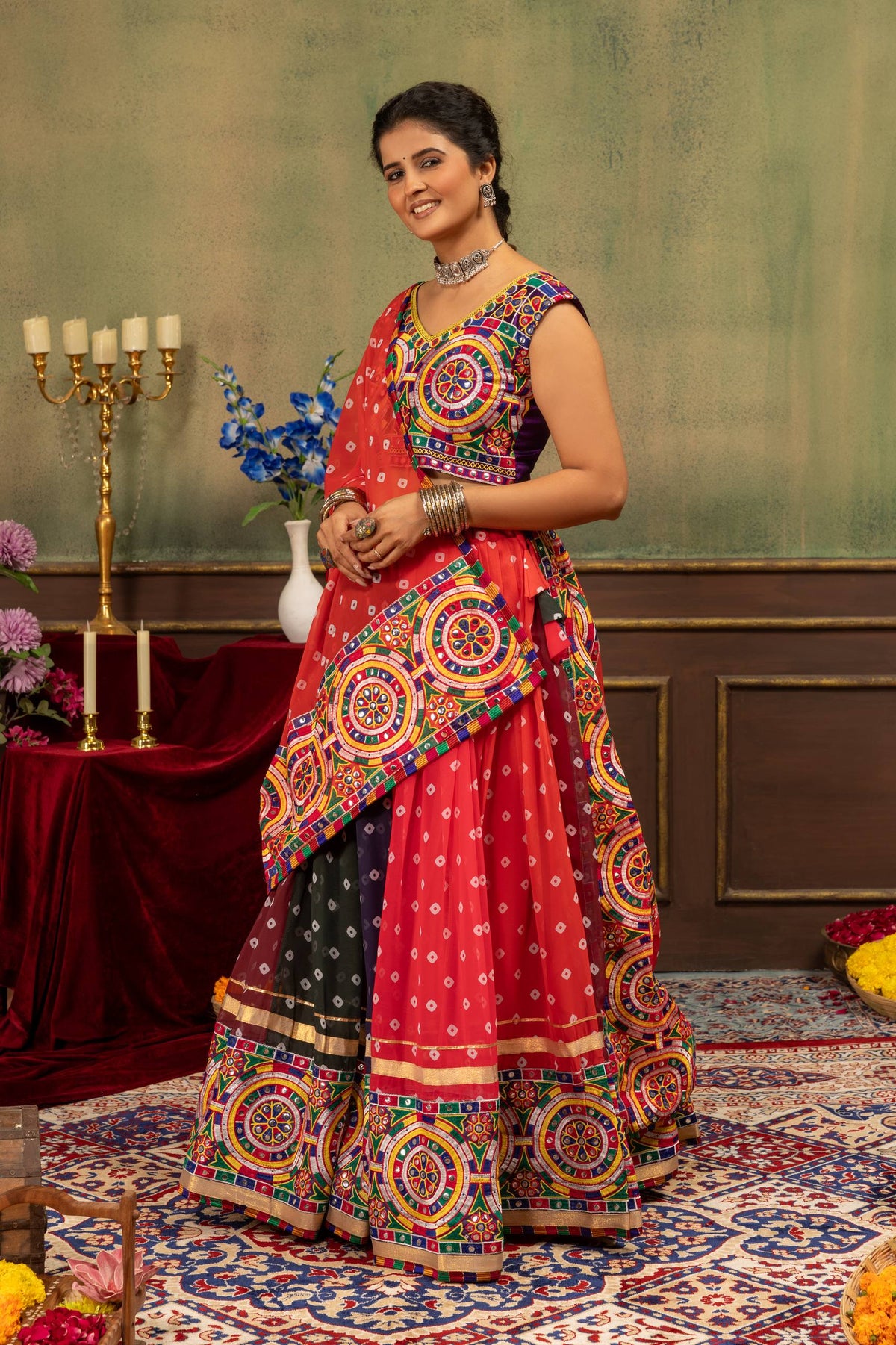Full-length view of model standing in red and dark blue panelled bandhani lehenga with embroidered blouse