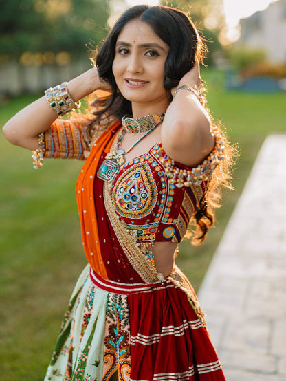 Mid-shot view of model wearing a red square-neck blouse with colorful teardrop mirror embroidery and draped orange dupatta