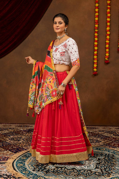 Three-quarter standing pose of a model dressed in a red lehenga with broad gold hemline borders and a white embroidered choli.