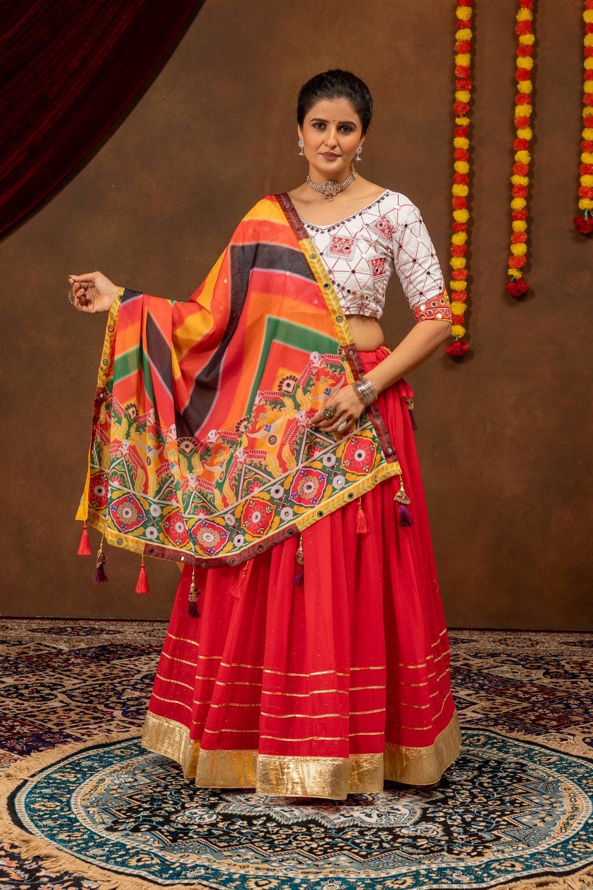 Full front view of a model wearing a red lehenga with gold border stripes, paired with an open multicolor printed dupatta.