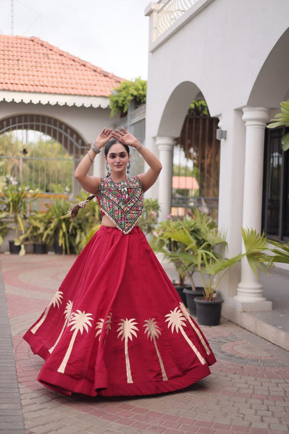 Red lehenga choli with multicolored patterned blouse and cream floral skirt detailing in a raised-arm pose