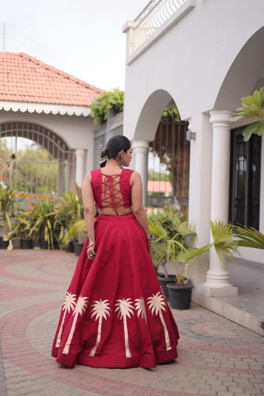 Back view of red lehenga choli showing the lace-up blouse and cream floral skirt detailing