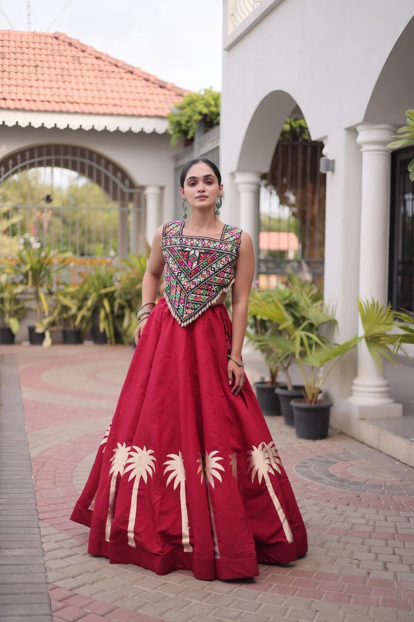 Red lehenga choli with multicolored patterned blouse and cream floral skirt detailing in a standing pose