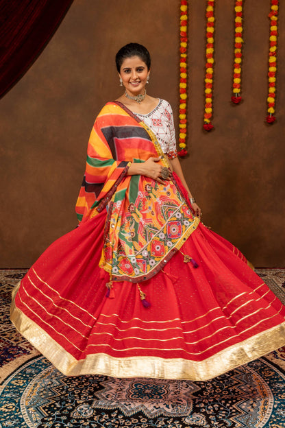 Model displaying the wide circular flare and horizontal gold border stripes of a red pleated lehenga skirt.