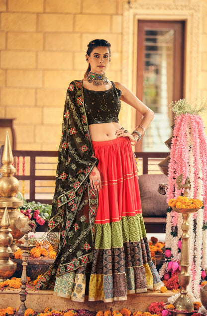 Standing full-length shot of model wearing a black sleeveless crop choli and red tiered flare lehenga with an embroidered black dupatta drape
