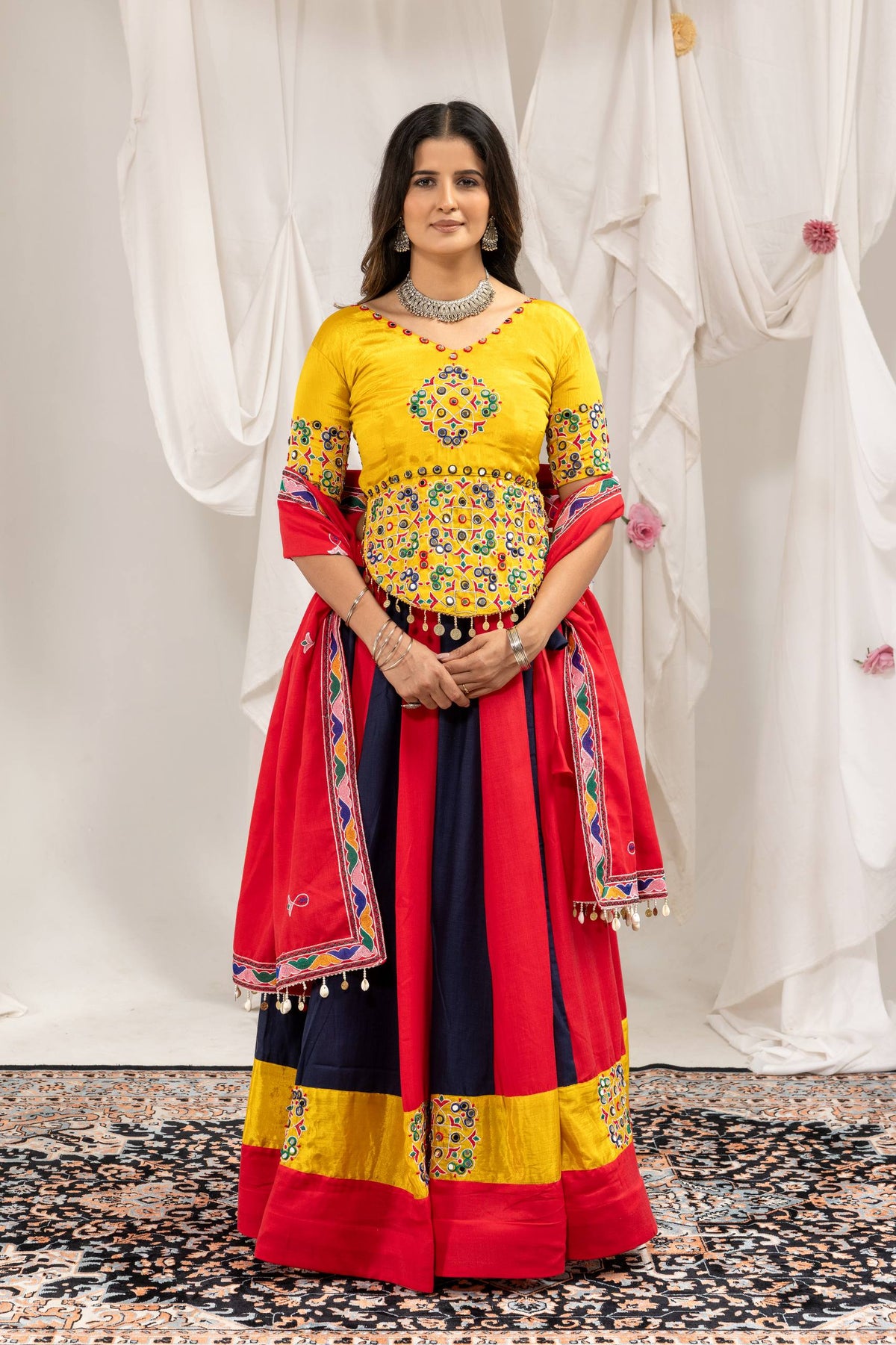 Full-length front view of model standing in red and dark blue panelled lehenga choli set with matching red dupatta