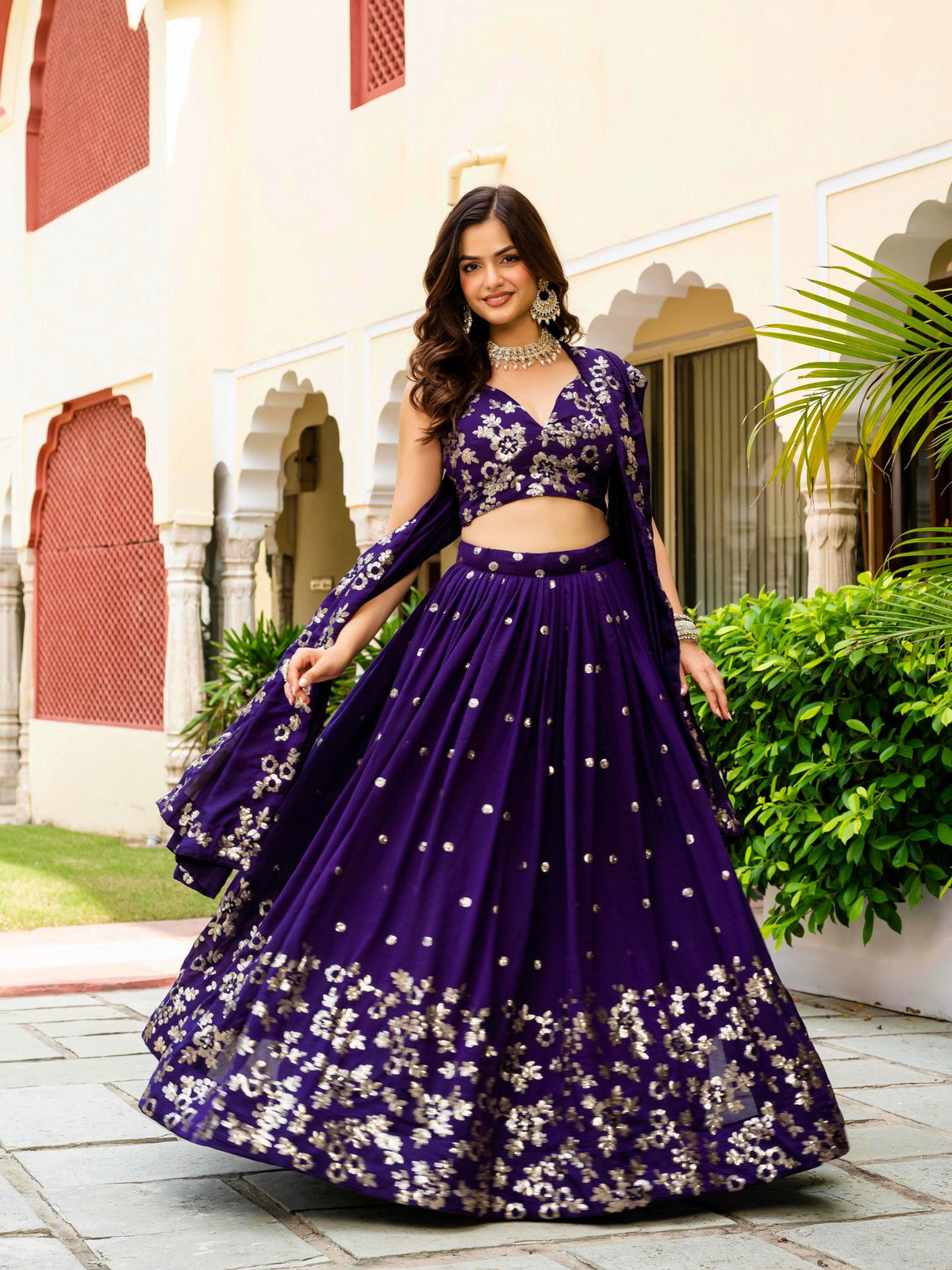 Full shot displaying the wide flare and gold floral work on a royal purple traditional lehenga skirt