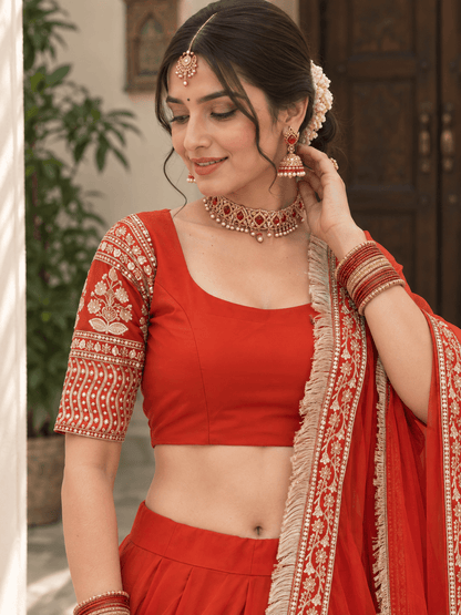 Close-up of rust orange U-neck blouse featuring gold floral sleeve embroidery and fringe-bordered dupatta drape