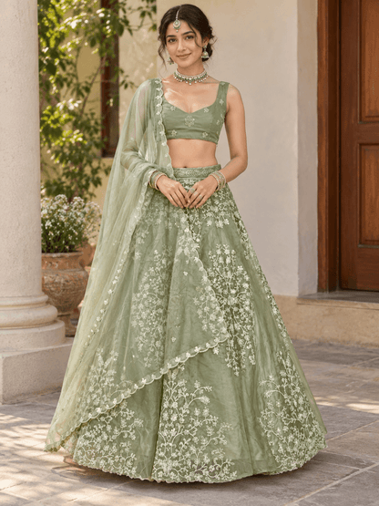 Model wearing flared sage green lehenga with white floral thread embroidery and scalloped dupatta