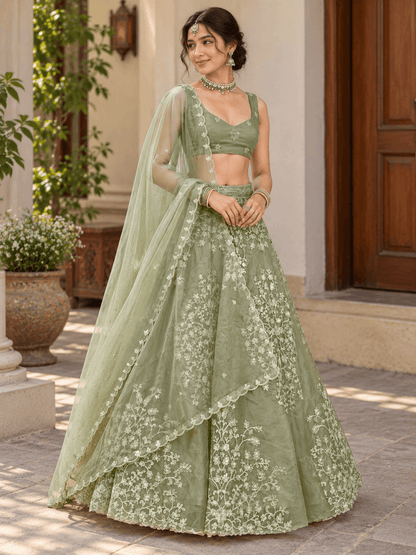 Full-length pose of model in sage green flared lehenga choli with delicate floral thread work