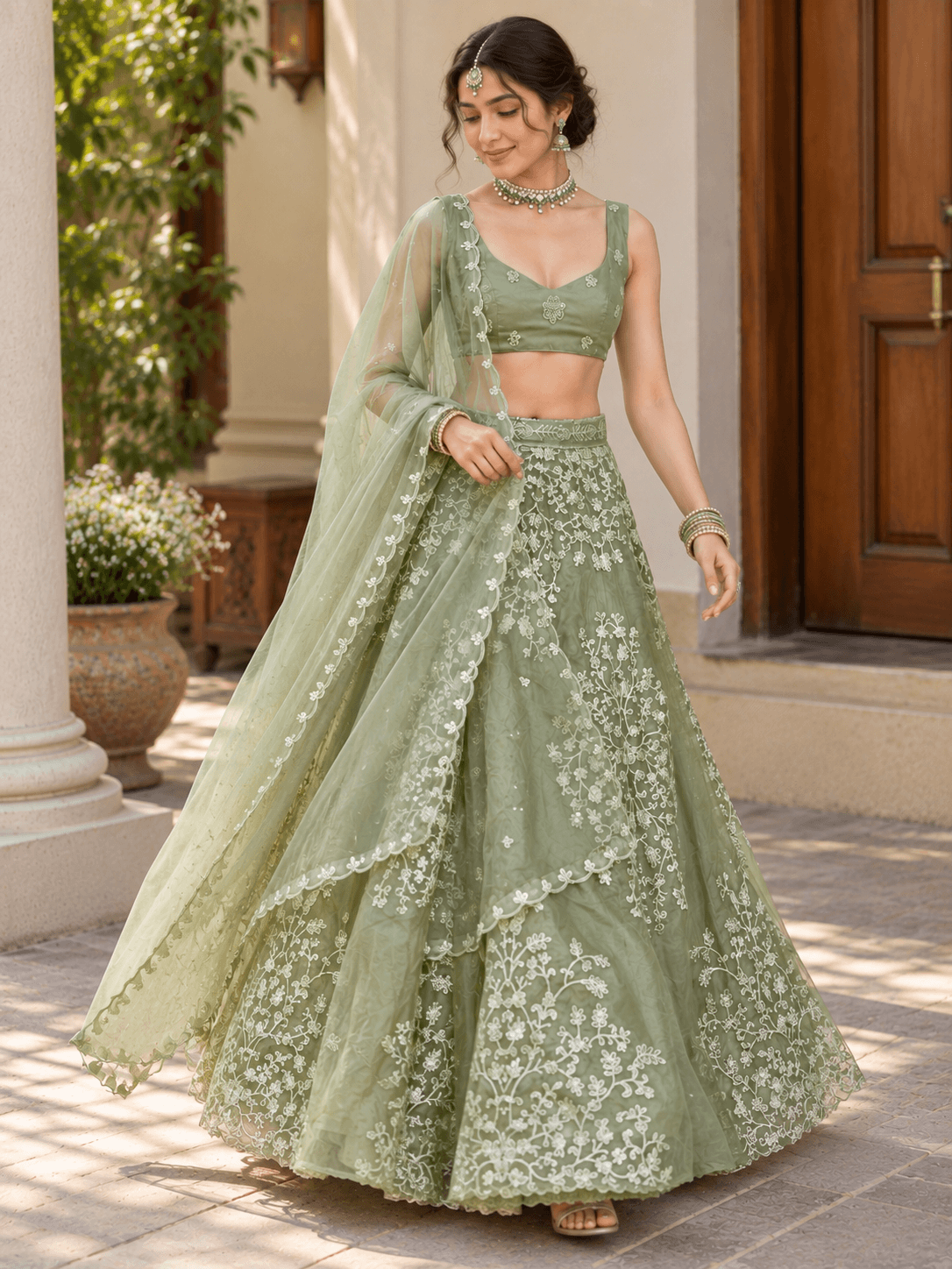 Straight front shot of model dressed in sage green embroidered lehenga set with scalloped border dupatta