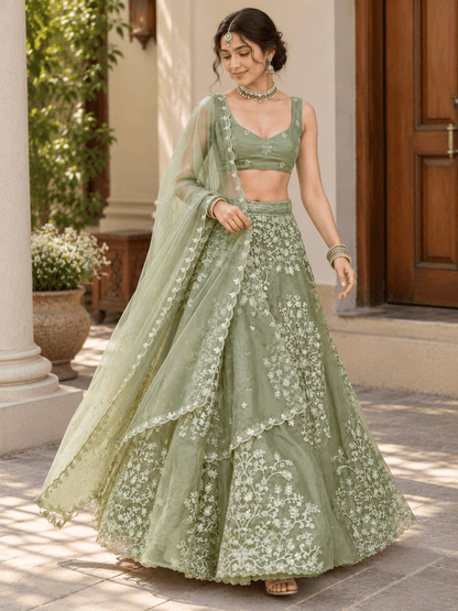 Straight front shot of model dressed in sage green embroidered lehenga set with scalloped border dupatta