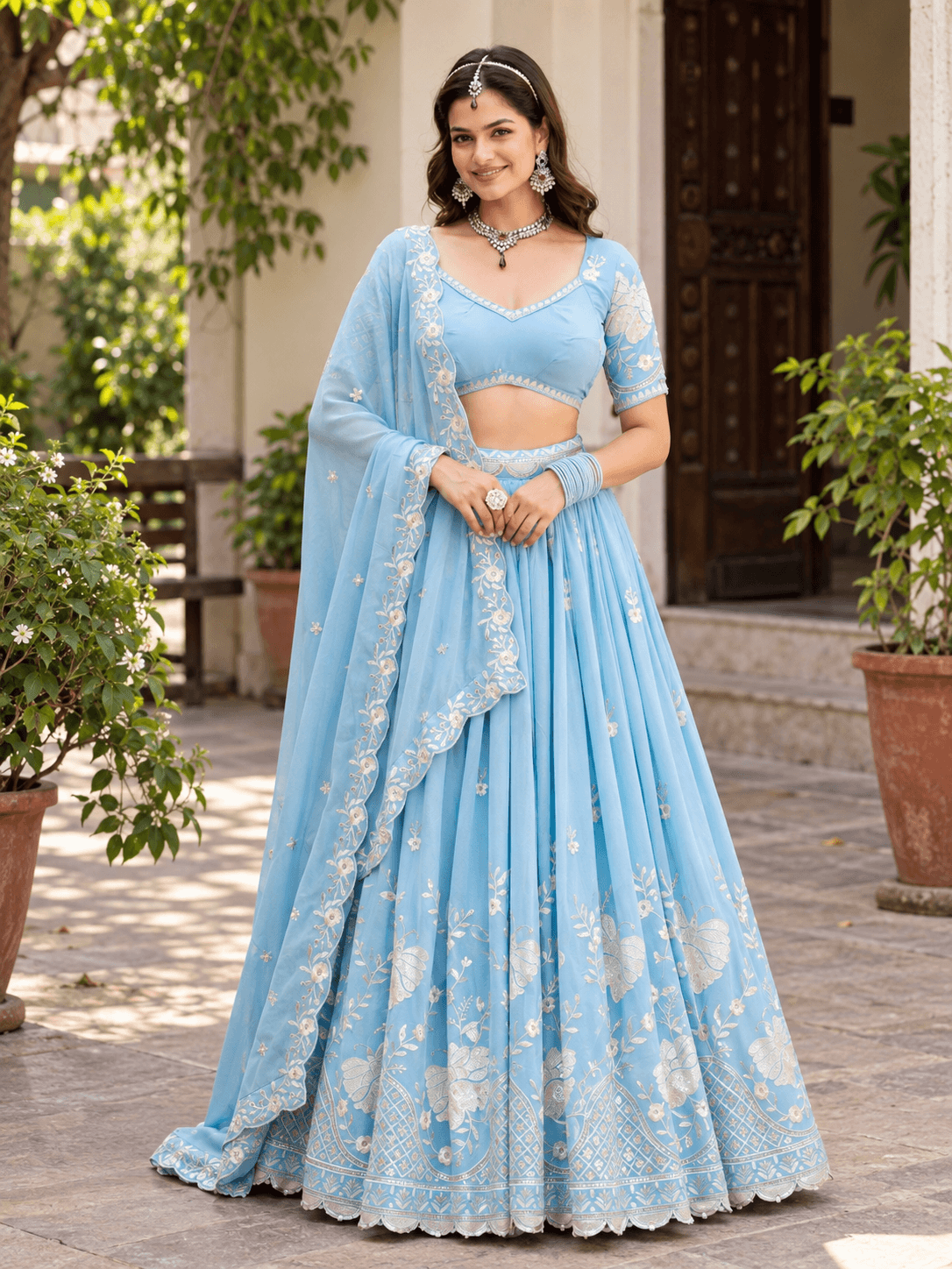 Full-length front shot of model in sky blue flared lehenga choli featuring floral embroidery and scalloped dupatta