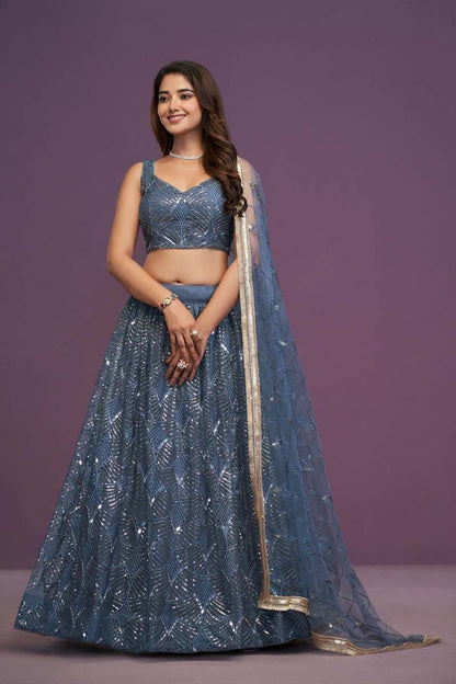 Full-length front view of model wearing slate blue embroidered sequin lehenga choli with gold border dupatta