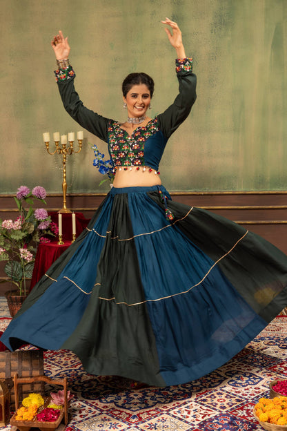High-angle twirling view of model showing full flare of teal blue and black panelled tiered lehenga skirt
