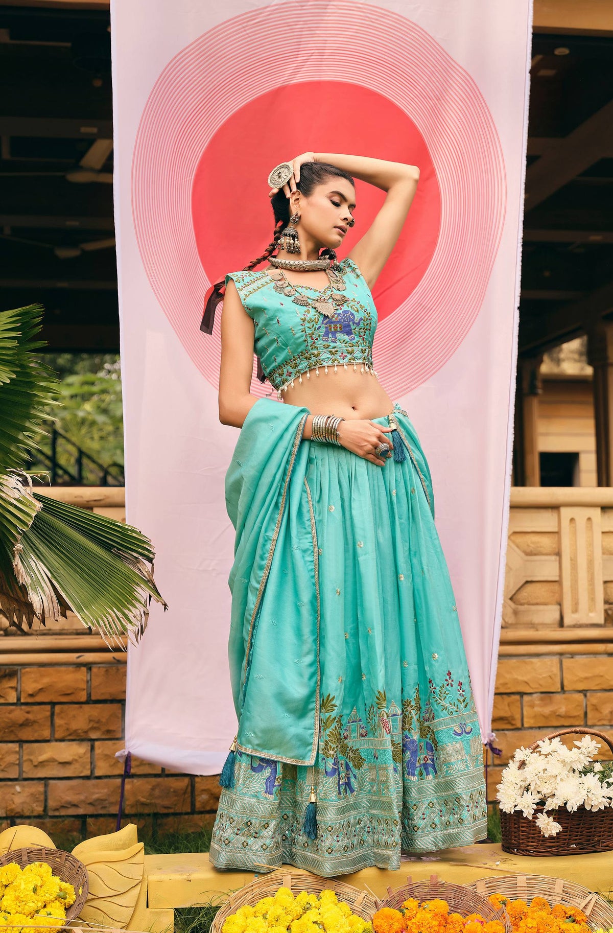 Standing side pose of a model in a turquoise blue embroidered lehenga choli with side-draped dupatta