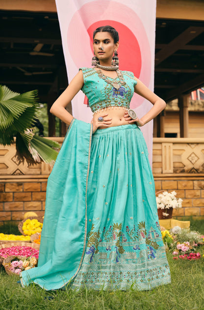 Full-length front view of a model in a turquoise blue pleated lehenga choli set with matching draped dupatta